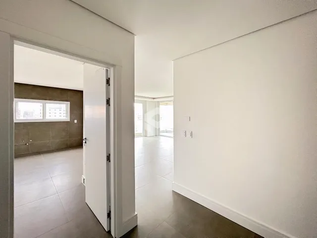 Hall de entrada com piso claro e paredes brancas.
