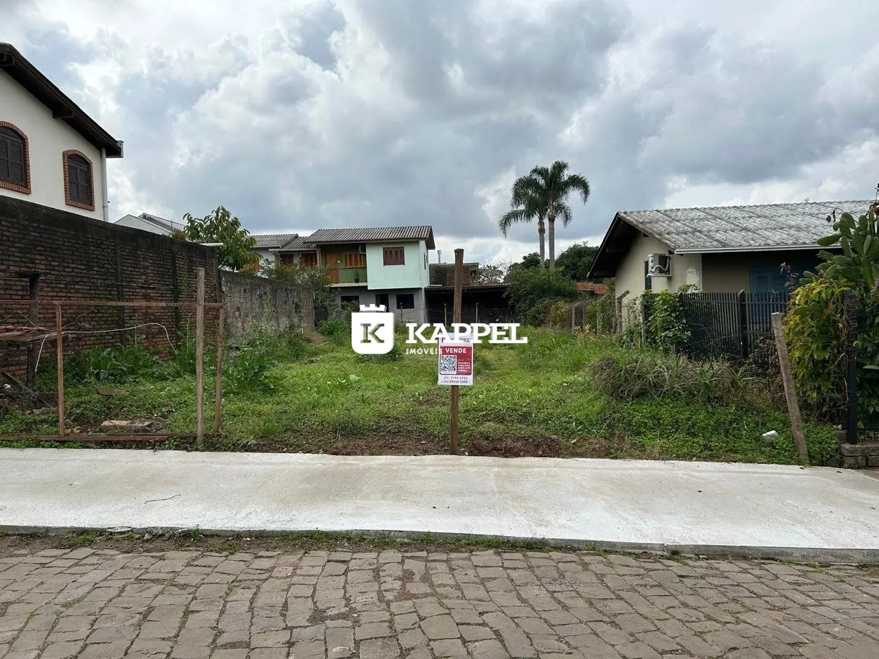 Vista externa de uma residência com muro de tijolos e vegetação.