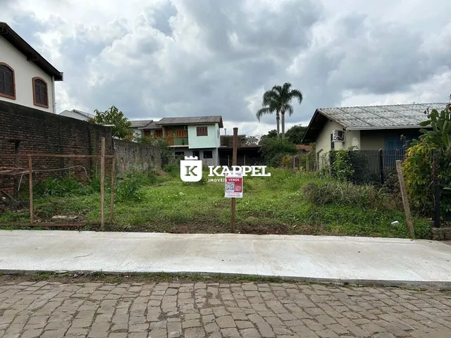 Vista externa de uma residência com muro de tijolos e vegetação.