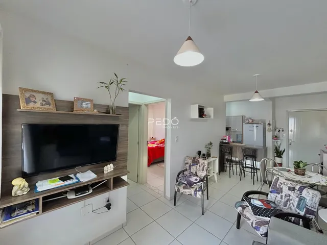 Sala de estar com televisão e estantes de madeira em um imóvel no Brasil.