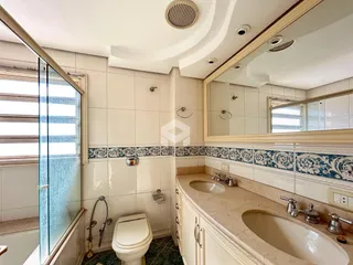 A foto mostra um banheiro com azulejos brancos e bancada de mármore.