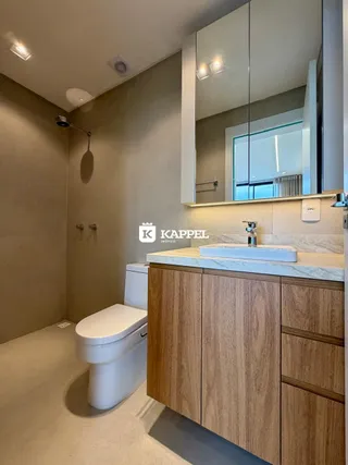 Banheiro com bancada de madeira e vaso sanitário.