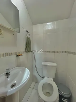 Foto de um banheiro com azulejos brancos e louças sanitárias.