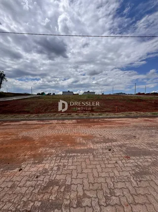 Vista da propriedade com terreno e estrada no primeiro plano.