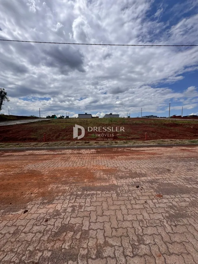 Vista da propriedade com terreno e estrada no primeiro plano.