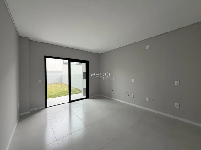 Interior de um ambiente com porta de vidro abrindo para um jardim.