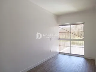 Ambiente interno de uma sala com piso de madeira e grande janela.