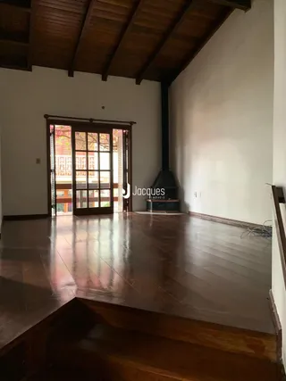 Interior de uma sala com piso de madeira e vigas de madeira.