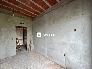 Foto de um cômodo interno com paredes de concreto aparente e teto de madeira exposta.