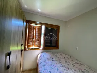 Quarto com cama e janela de madeira em um imóvel em Lajeado.