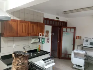 Vista interna de uma cozinha com armários de madeira e revestimento de azulejos.