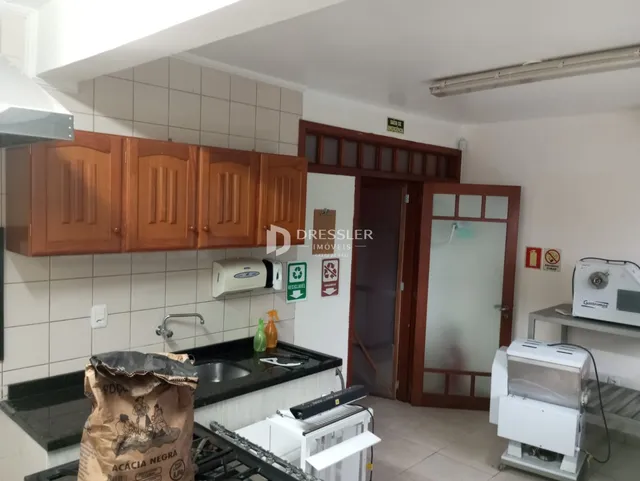 Vista interna de uma cozinha com armários de madeira e revestimento de azulejos.