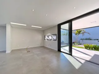 Ambiente interno amplo com piso de grande formato e porta de vidro.