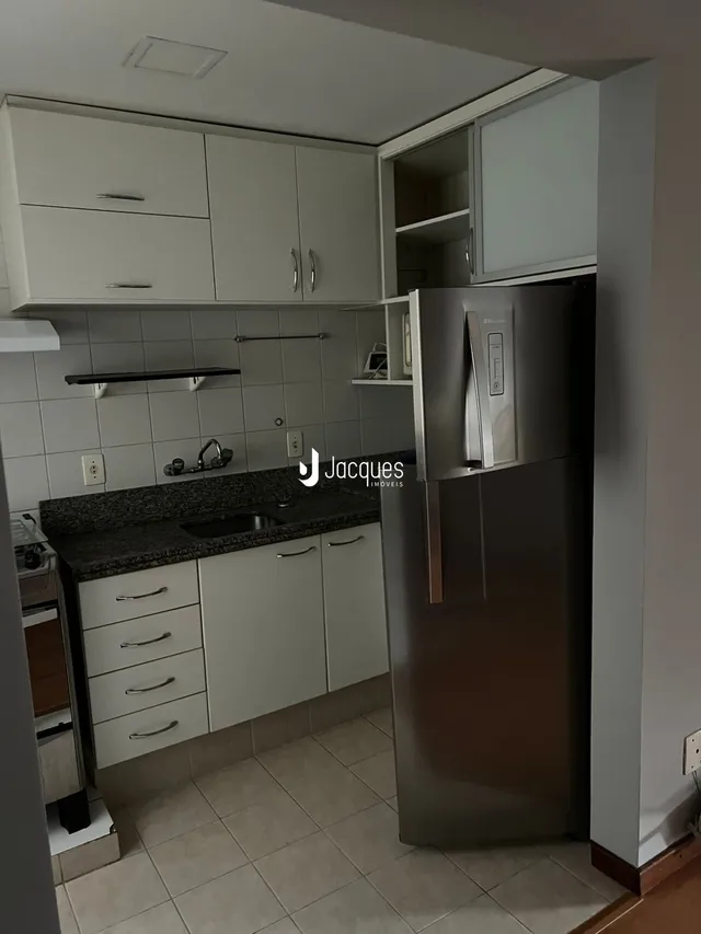 Foto de uma cozinha interna com armários brancos e bancadas escuras.