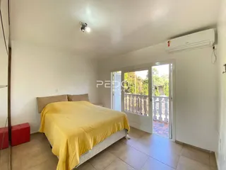 Quarto com cama e acesso a uma varanda através de porta de vidro.