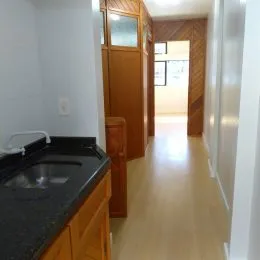 Corredor interno com revestimento de madeira e piso claro.