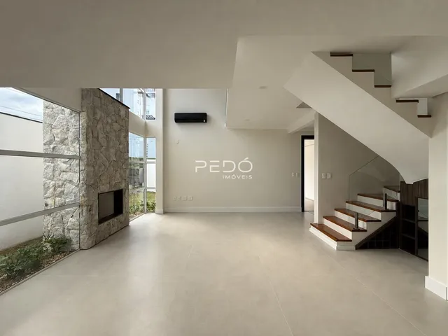 Sala de estar ampla com piso claro e parede de pedra em um imóvel em Lajeado.
