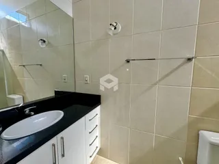 Banheiro com revestimento de cerâmica e bancada escura.