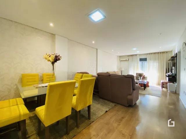 Sala de estar com cadeiras amarelas e piso de madeira.