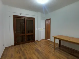 Interior de uma sala com piso de madeira e portas de madeira.