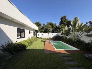Foto da área externa da residência mostrando o jardim e a piscina.