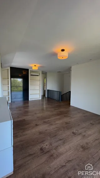 Vista de um ambiente interno com piso de madeira e estantes brancas.