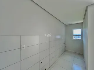Corredor interno de uma residência com paredes brancas e piso claro.