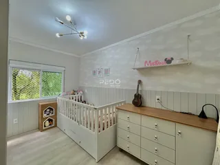 Quarto com cama de berço e armário de madeira clara em ambiente bem iluminado.
