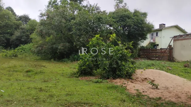 Vista externa de uma propriedade com área gramada e vegetação densa.