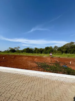 Vista da paisagem com terra vermelha e vegetação verde sob um céu azul.