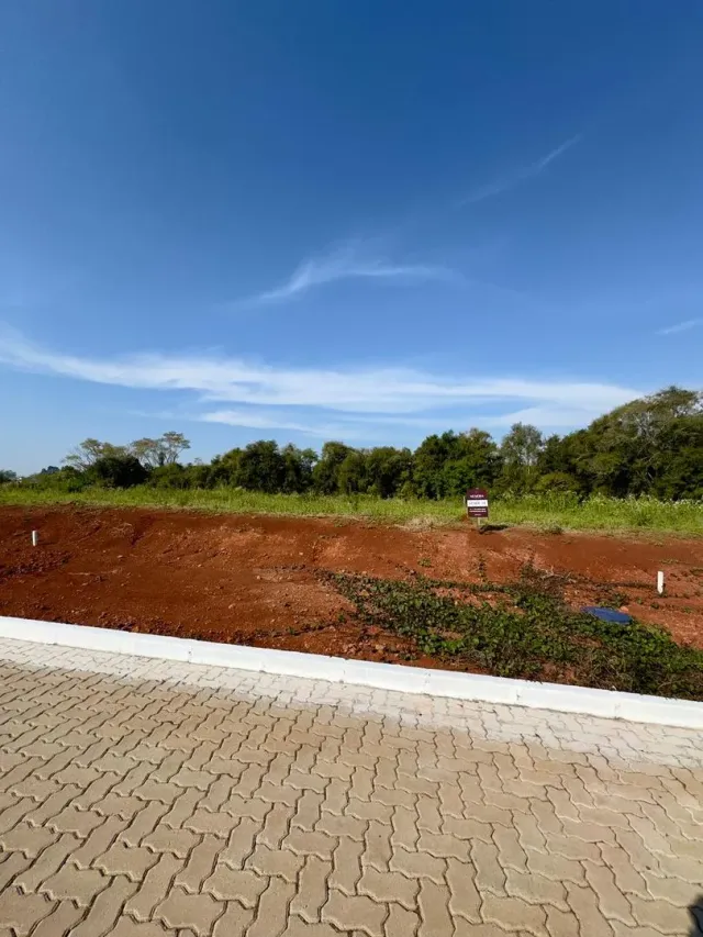 Vista da paisagem com terra vermelha e vegetação verde sob um céu azul.