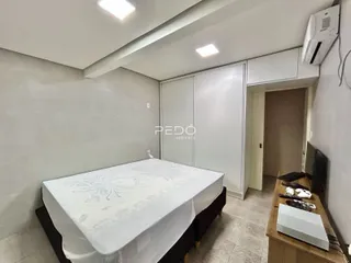 Quarto com cama arrumada e armários brancos