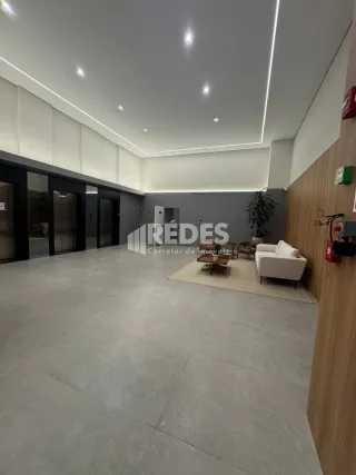 Interior de um espaço amplo com piso de concreto e paredes claras.
