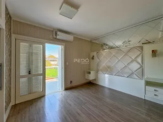 Sala de estar com piso de madeira e porta de vidro abrindo para a vista.