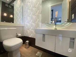 Banheiro com revestimento branco e louças modernas.
