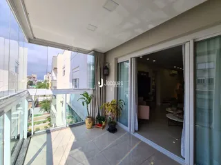 Vista interna de uma sala de estar com grandes janelas de vidro.
