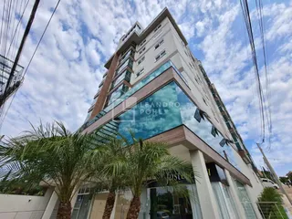 Fachada moderna de um edifício residencial em Lajeado, Brasil, com grandes painéis de vidro e vegetação.
