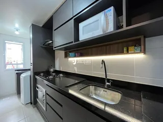 A cozinha apresenta armários escuros e bancadas modernas.