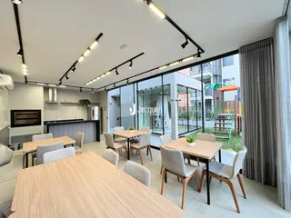 Interior de uma sala de estar com mesa de jantar e acesso a uma área externa.