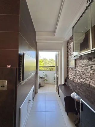 Hall de passagem interno com piso de cerâmica claro e vista para o exterior.