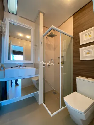 Banheiro com box de vidro e bancada.