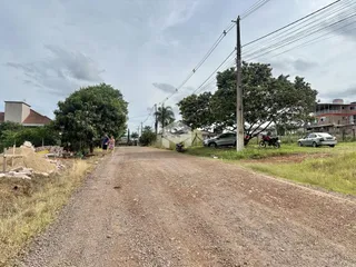 Vista de uma estrada de terra em uma área residencial no Brasil.