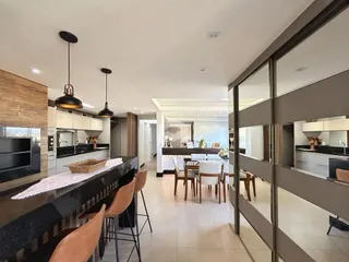 Ambiente interno de uma sala de estar com cozinha integrada e área de jantar.