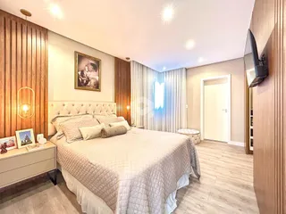 Quarto com cama grande e painel de madeira na sala.