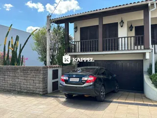 Fachada de uma casa residencial em Lajeado, Brasil, com garagem e paisagismo frontal.