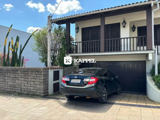 Fachada de uma casa residencial em Lajeado, Brasil, com garagem e paisagismo frontal.