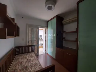 Quarto com cabeceira de madeira e armário em um apartamento no Brasil.
