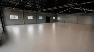 Espaço interno amplo com piso liso e teto industrial.