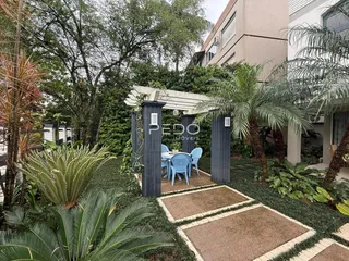 Vista externa de um jardim com área de lazer e paisagismo.