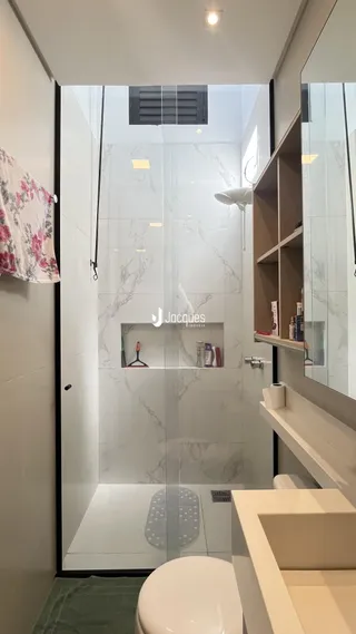 Banheiro moderno com revestimento em mármore e vidro.